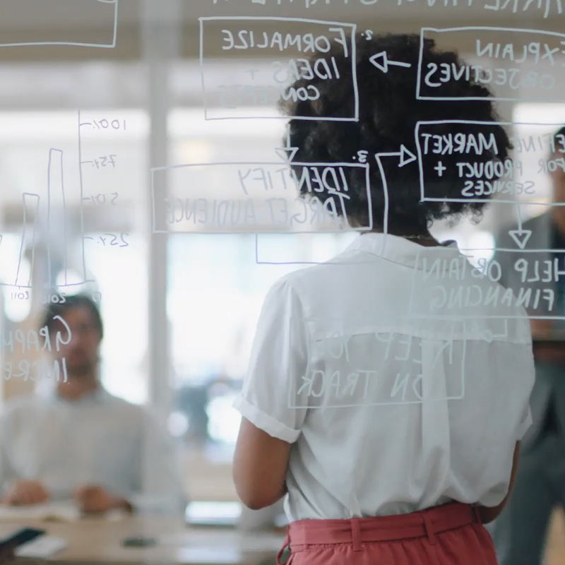 a woman looking at a glass wall with writing on it