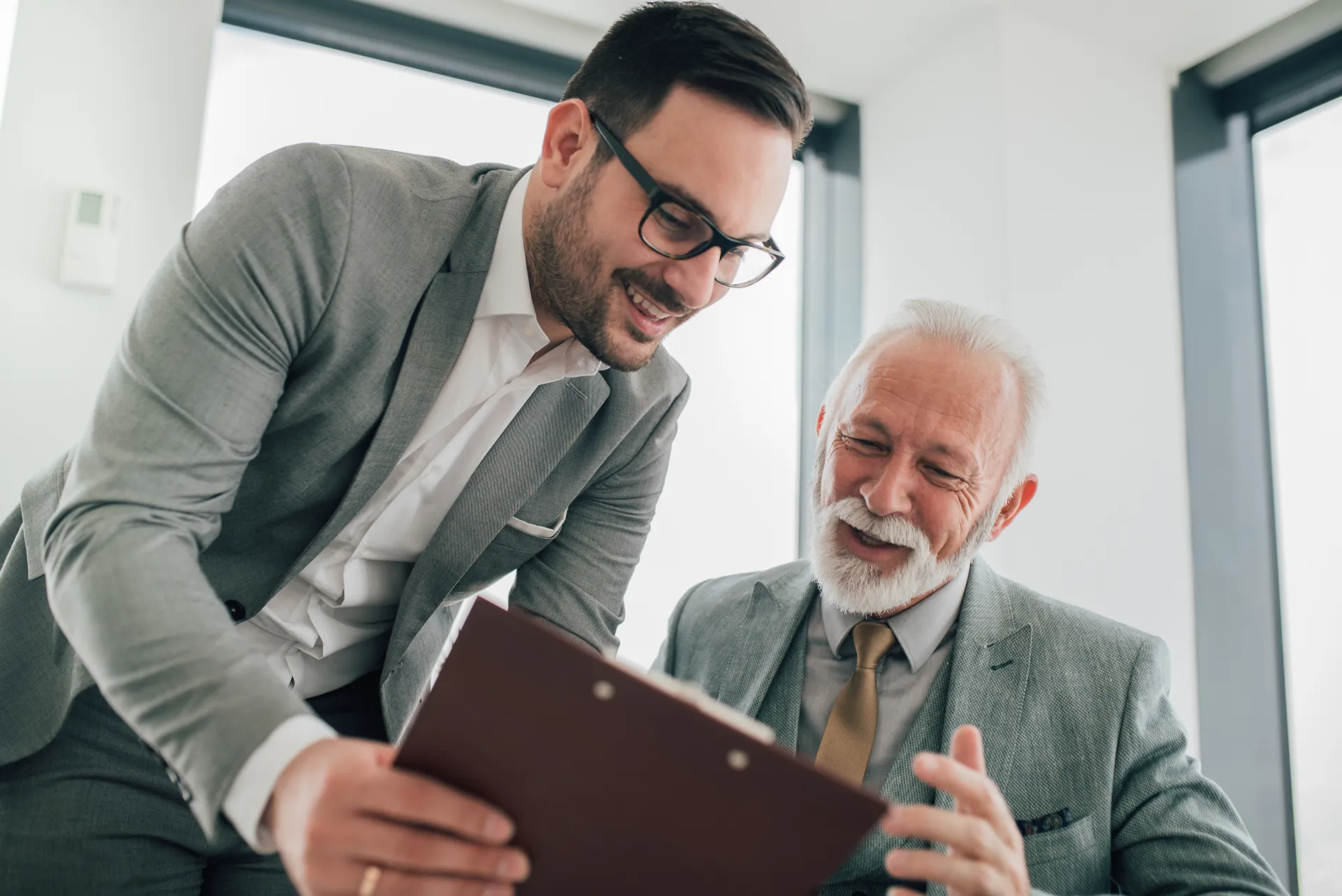 a man looking at a clipboard with another man smiling a man looking at a clipboard with another man smiling