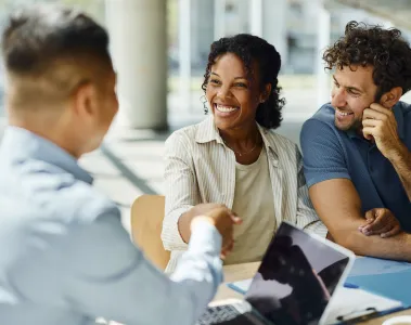 a group of people sitting at a table shaking hands